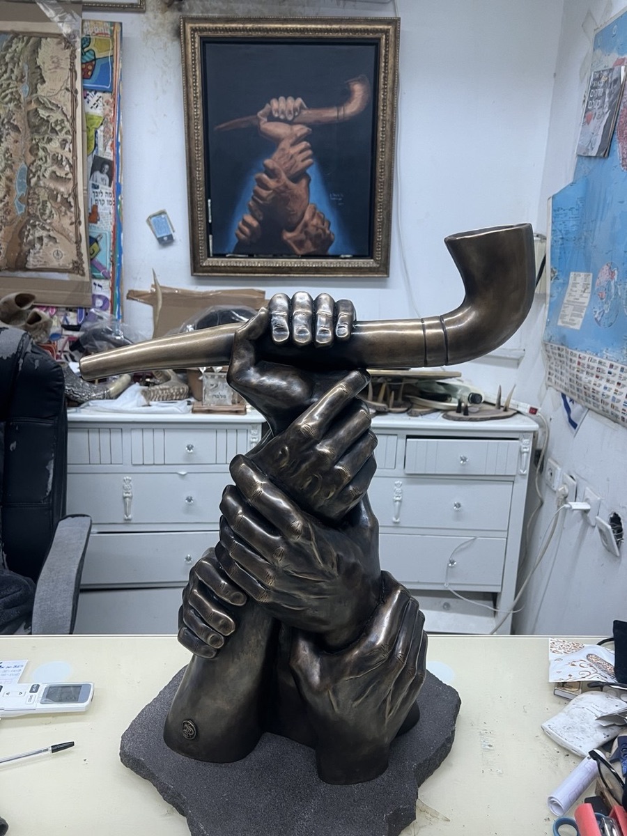 The finished bronze sculpture in the studio, with the original painting visible behind it