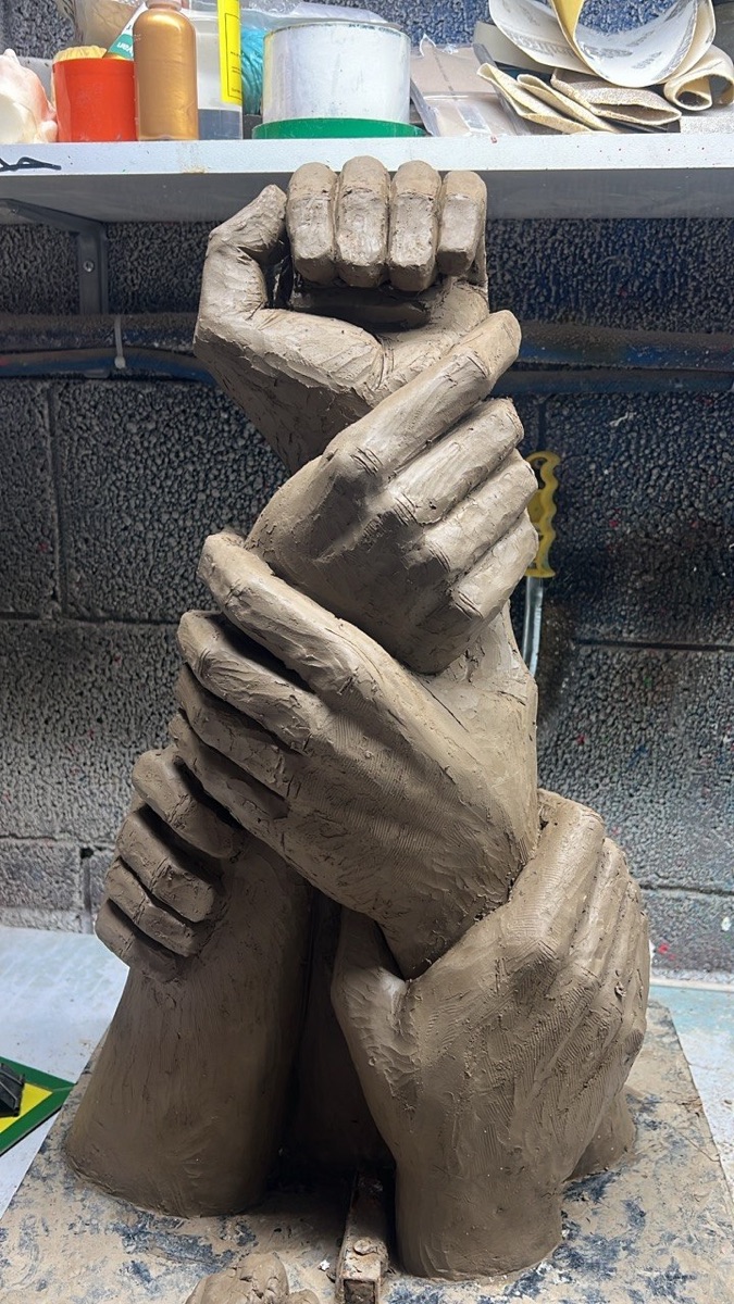 Clay model of The Great Shofar — intertwined hands gripping the shofar, front view